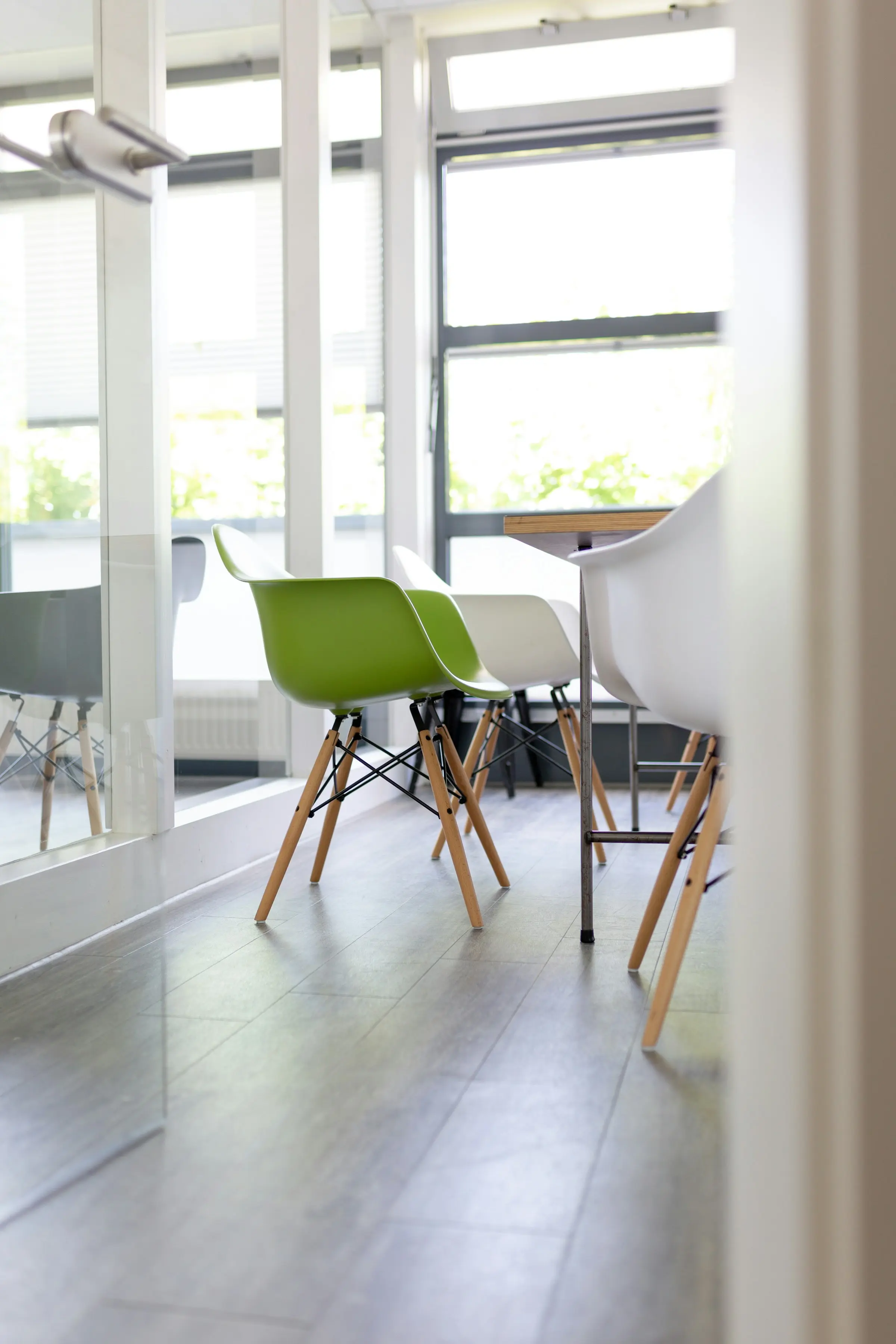 A number of green and white chairs seen through an open glass door